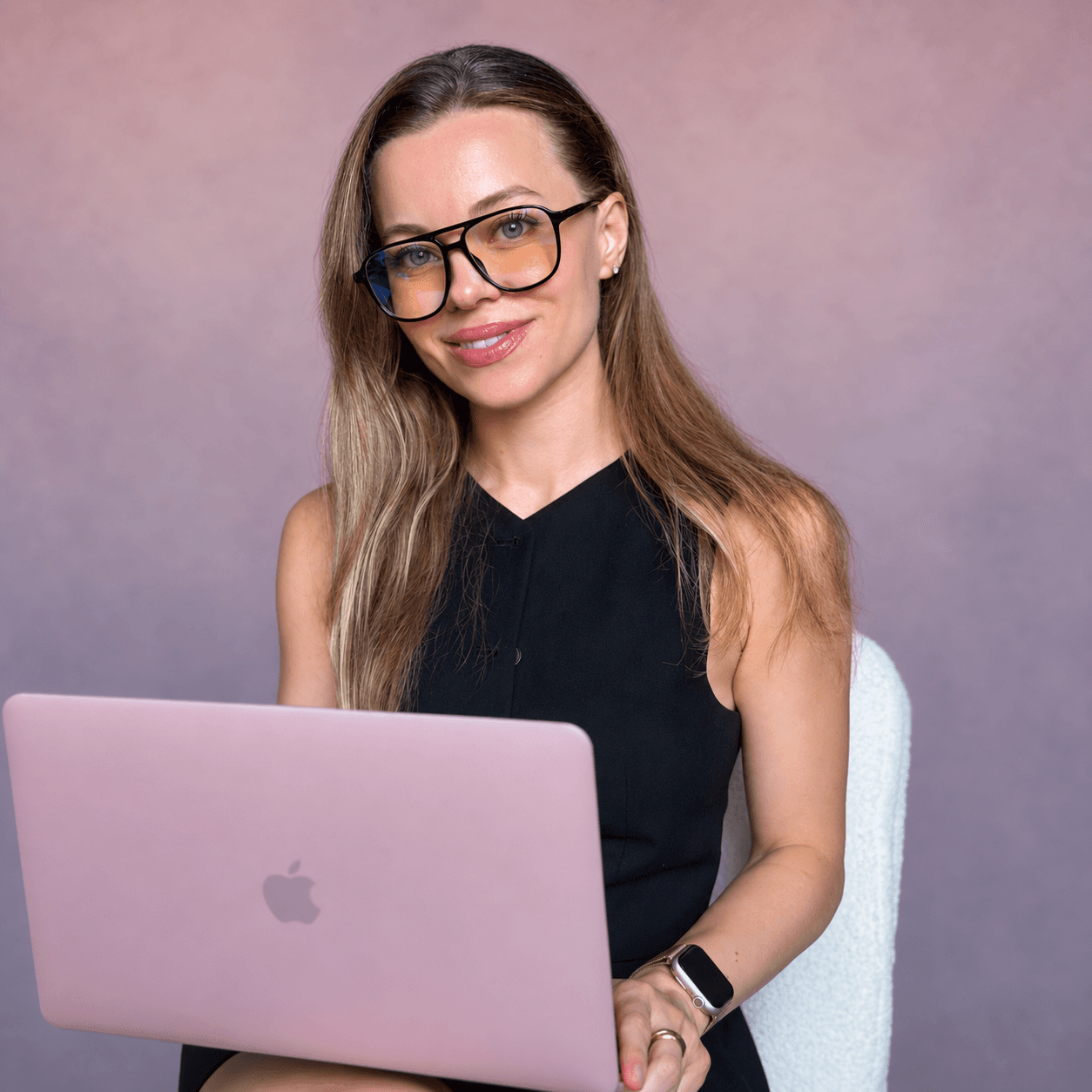Tania Solovey smiling at her laptop, wearing glasses